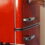 An arm extends to open a vintage-style red refrigerator, creating a nostalgic kitchen scene.